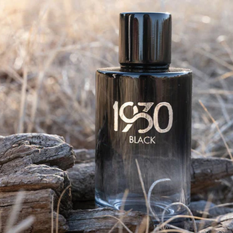 A bottle of '1930 Black' cologne placed on a wooden surface with a natural background.