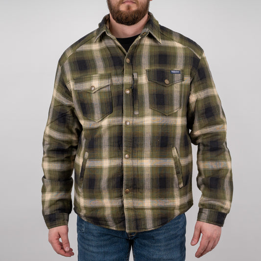 Man wearing a long-sleeved green plaid men's shirt jacket with hand warming pockets and snap closures on a gray background.