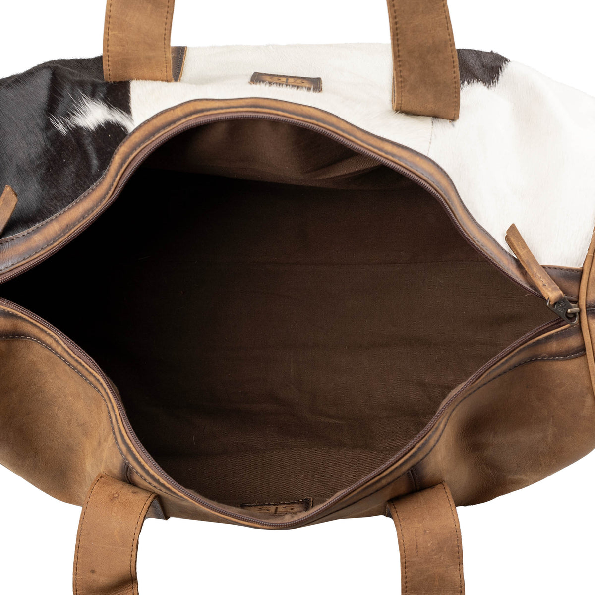 Inside compartment of duffle bag with brown genuine leather accents, hair on hide cowhide and zip closure on a white background.