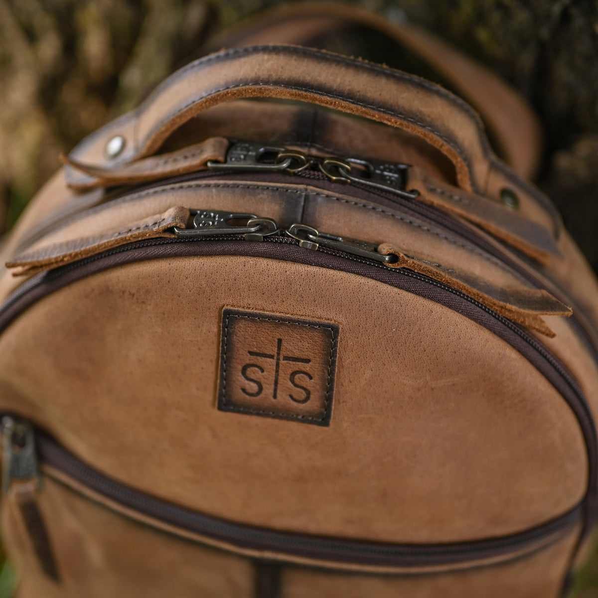 Brown genuine leather backpack featuring leather carrying handle, zip closure and brown leather patch with STS Ranchwear embossed logo.