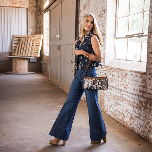 Terryn Cooper wearing a floral patterned vest, bellbottom jeans with heels and a cowhide and STS leather shoulder bag.