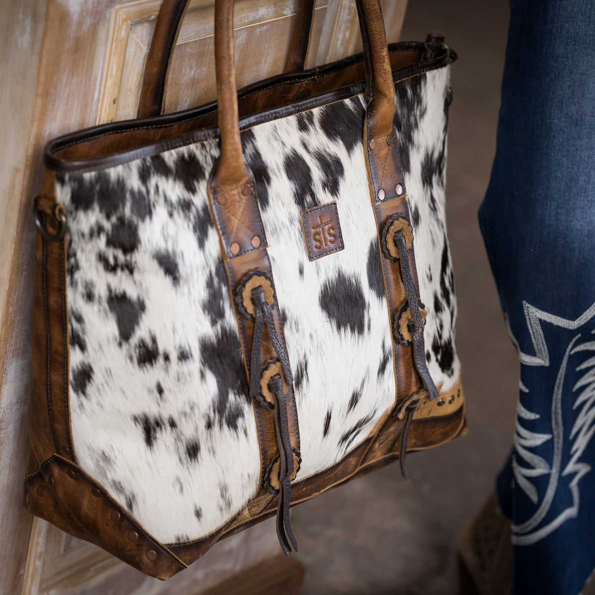 closeup of our cowhide and distressed full grain leather purse with top zip closure, two top carry handles and removable tassel