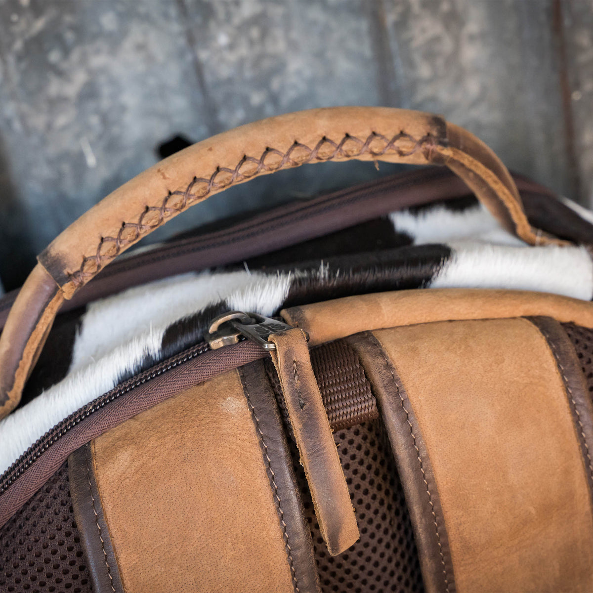 Detail on genuine leather carry handle on cowhide theo backpack.