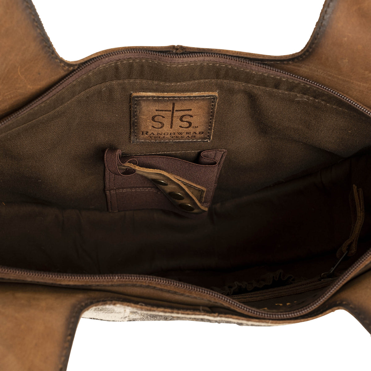 Inside main compartment with concealed carry pocket and brown leather patch with STS Ranchwear logo embossed.