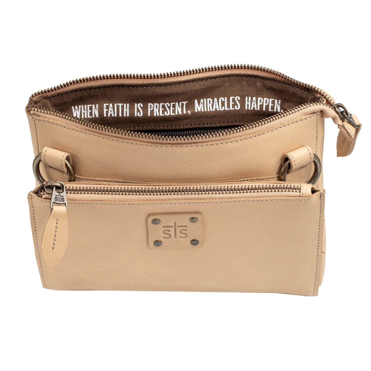 A beige leather crossbody with the quote: "when faith is present, miracles happen." in the lining of the top zip closure on a white background.