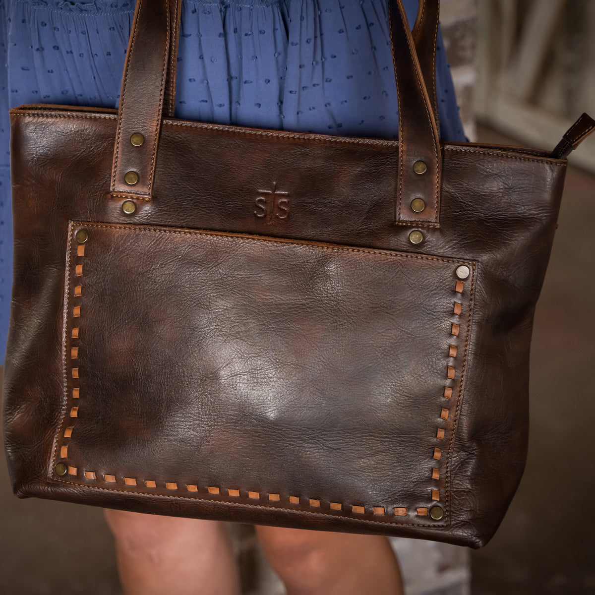 closeup of our bandera chocolate leather tote with top zip closure, two top carry handles, front magnetic pocket and back zip pocket