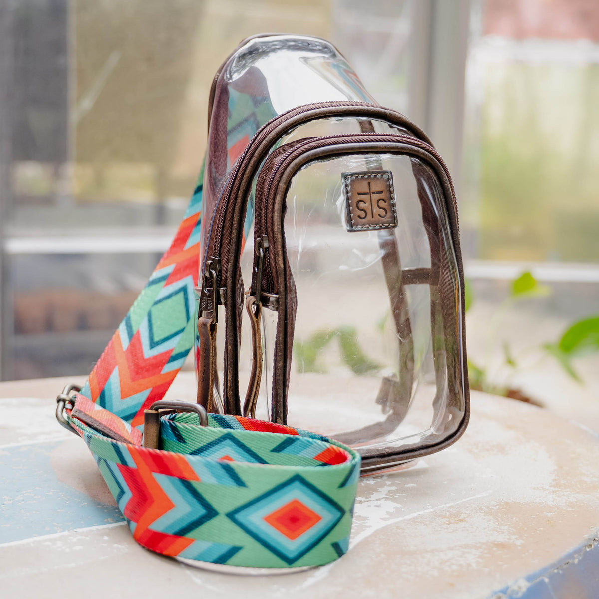 Clear pouch with colorful strap on a surface.