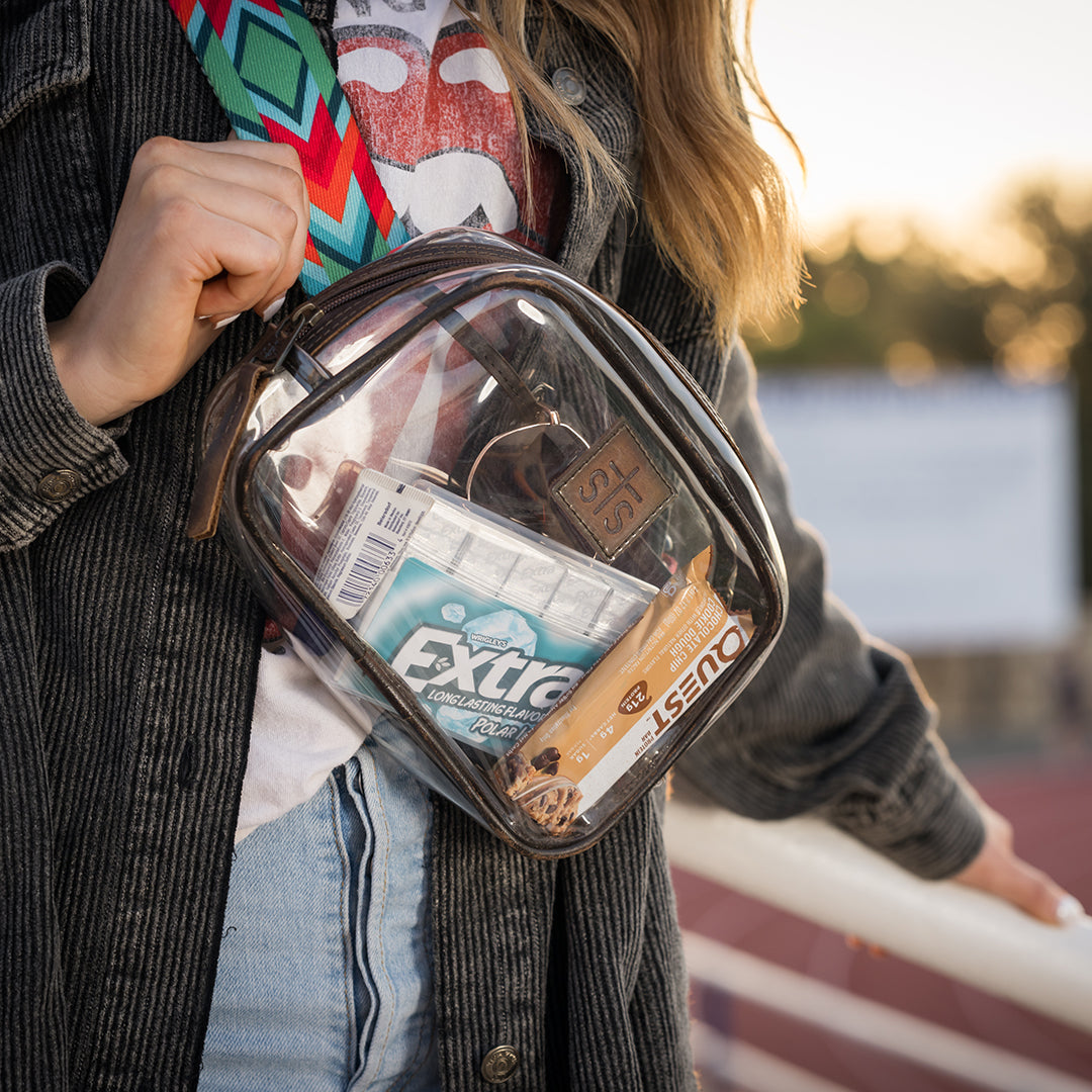 Person holding a clear bag with snacks, including a box of Extra gum, outdoors.