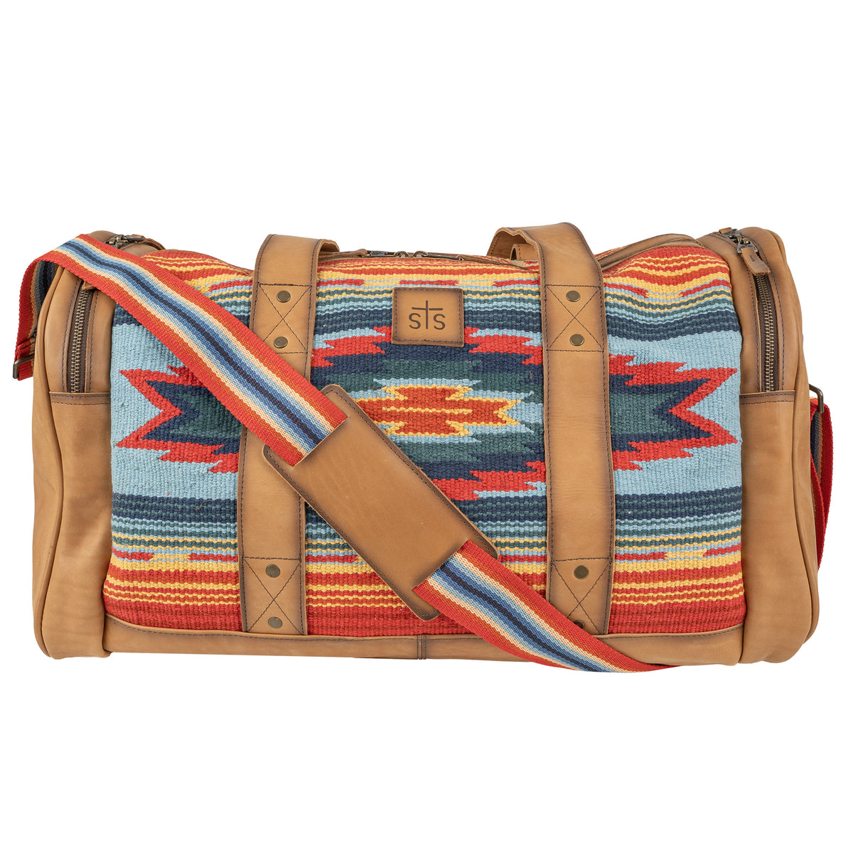A duffle bag with a vibrant geometric pattern in red, blue, and tan colors, featuring handwoven 100% cotton shell with genuine leather accents, and a shoulder strap.