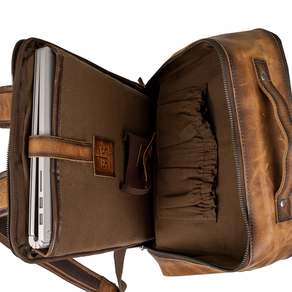 Inside compartment of cowhide backpack with scrunch pockets, laptop sleeve and a concealed carry pocket.