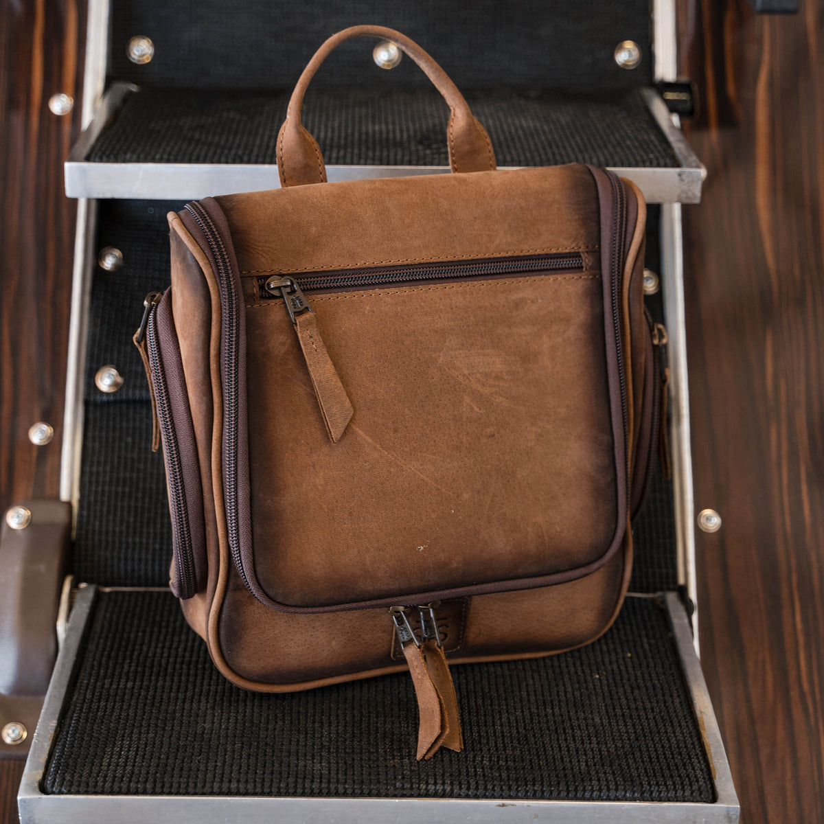 Brown genuine leather hanging shave kit with multiple compartments.