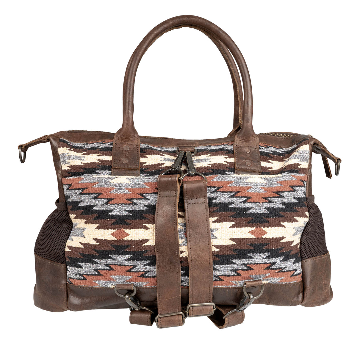 Multicolored patterned bag with brown leather backpack straps, trim and dual rolled leather handles on a white background.
