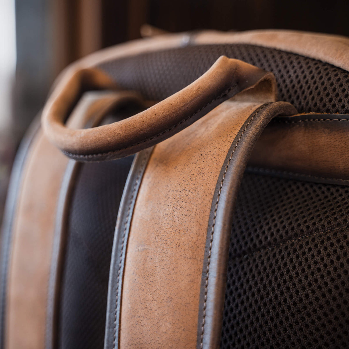 Details of genuine leather handle and padded backpack straps.