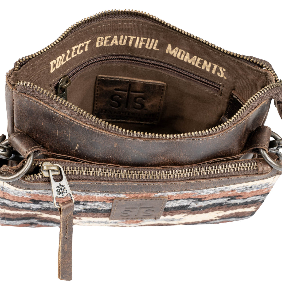Interior of brown leather bag with 'Collect Beautiful Moments' quote and zip pocket.