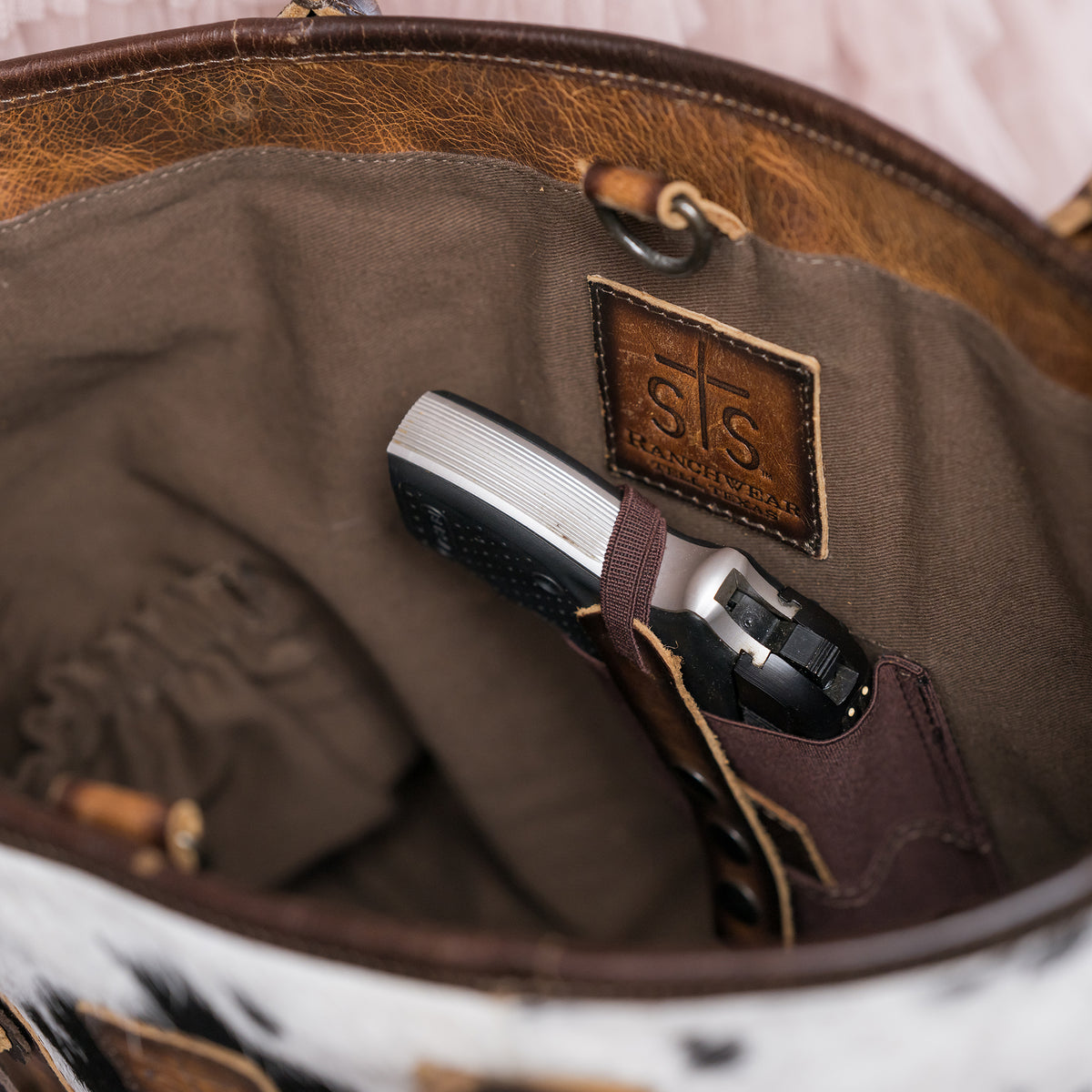 inside view of a weapon inside of our conceal carry compartment of our cowhide and distressed full grain leather purse with top zip closure, two top carry handles and removable tassel