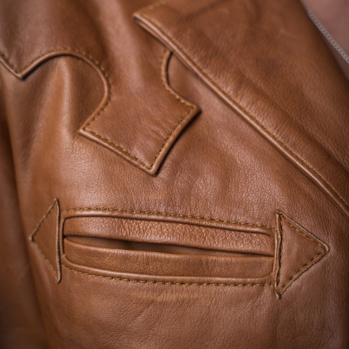Closeup of brown leather detail on a genuine leather jacket.