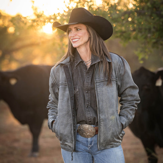 Jennifer Smith wearing the stonewash Rifleman leather jacket with zip closure in front of their black angus cattle.