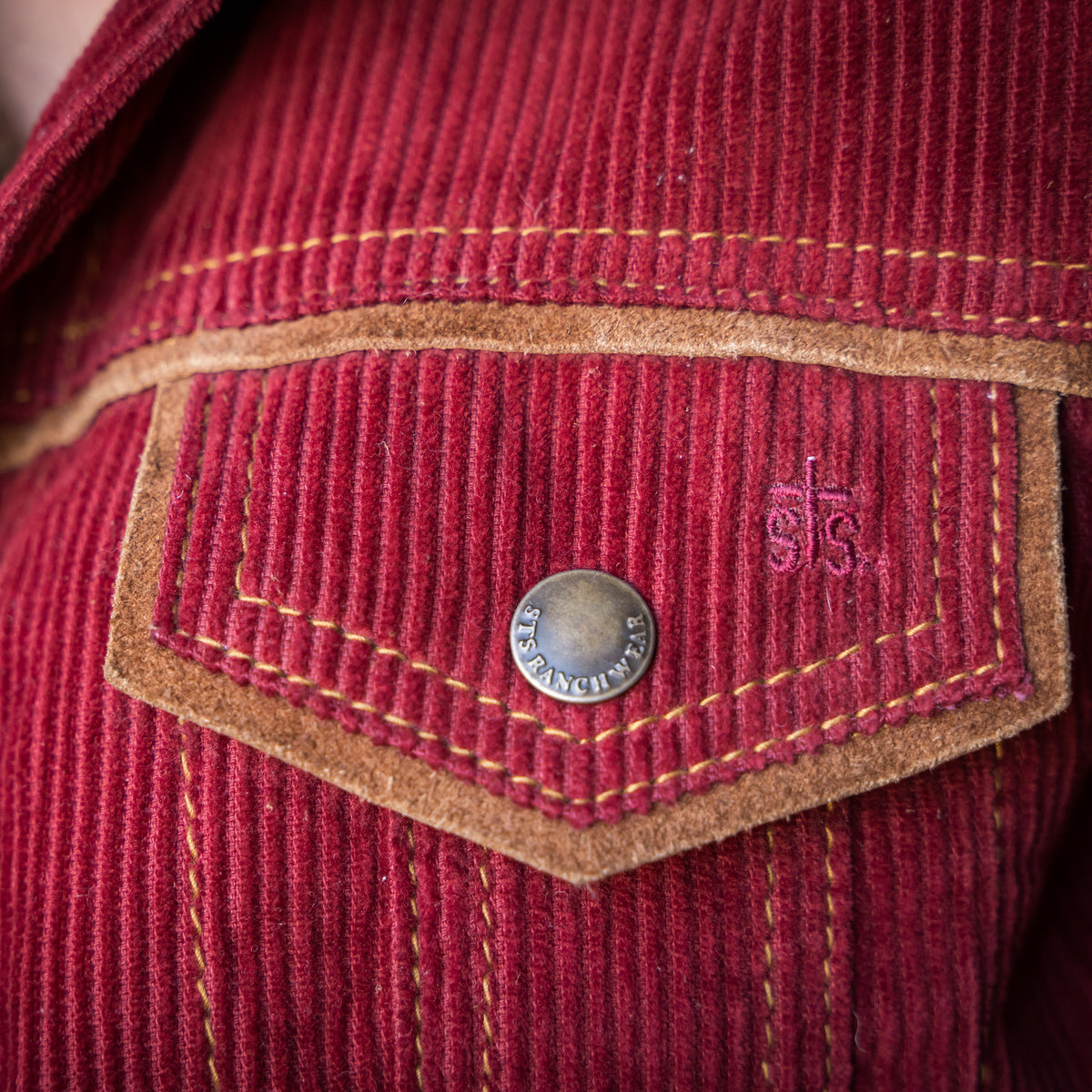 closeup of the chest pocket of our red cotton corduroy snap closure jacket with two chest pockets and leather collar details