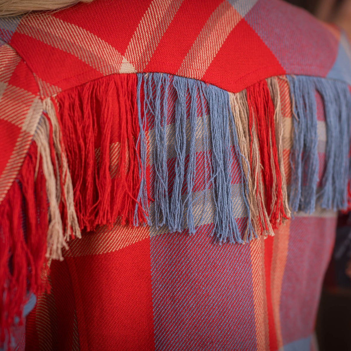 A red and blue plaid women's blazer with fringe accents on the back western yoke.