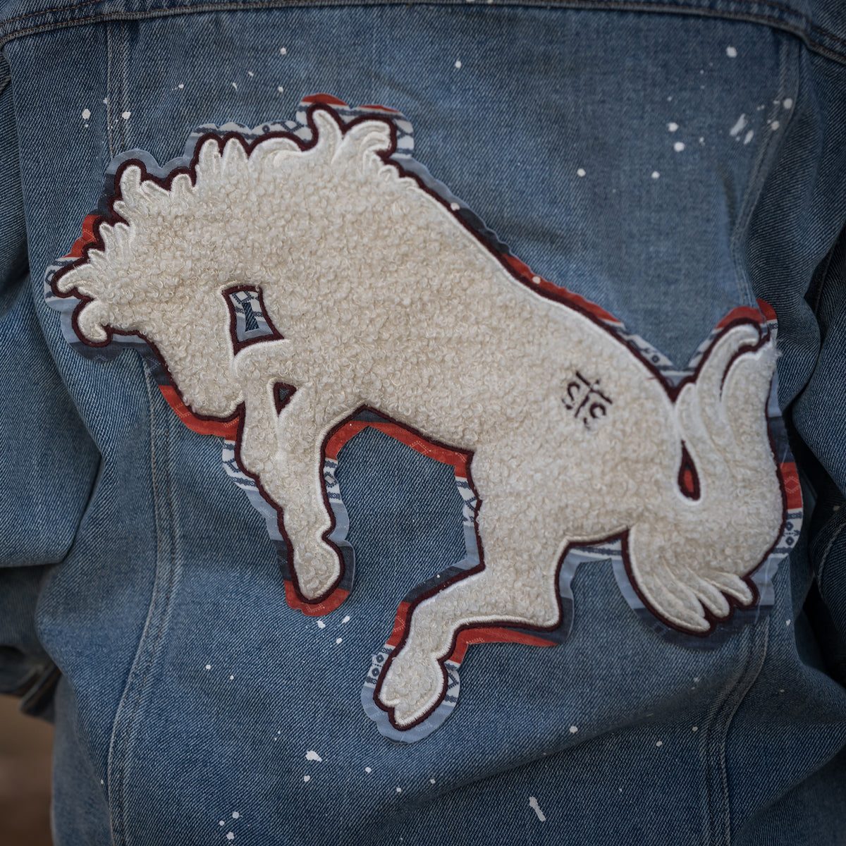 Closeup of hand drawn chenille back patch on denim jacket.