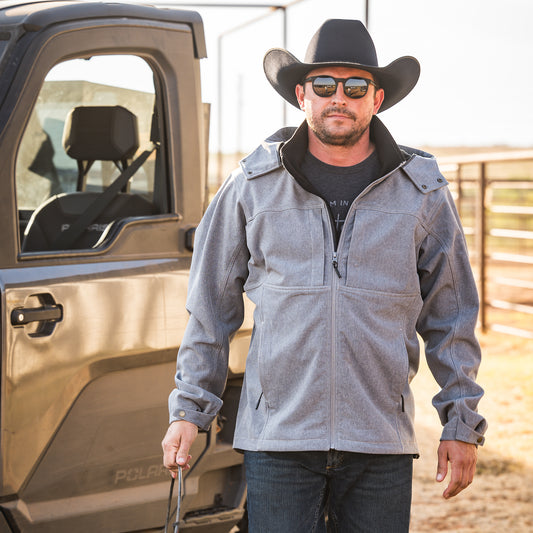 Vandon Vest wearing our gray jacket with zip closure, removable hood and hand warming pockets outside in front of a four wheeler