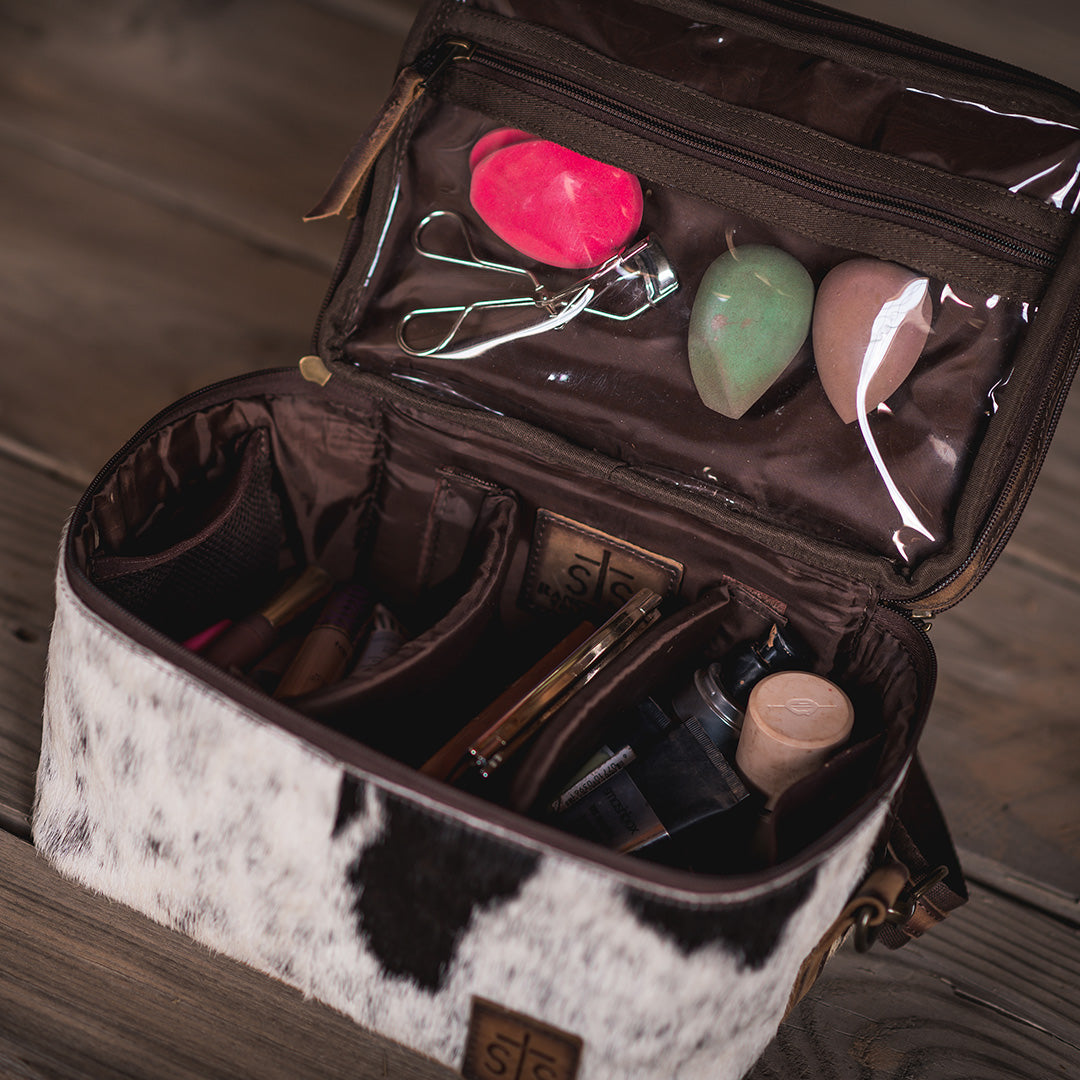 Inside view of hair on hide cowhide cosmetics bag with cosmetics inside.