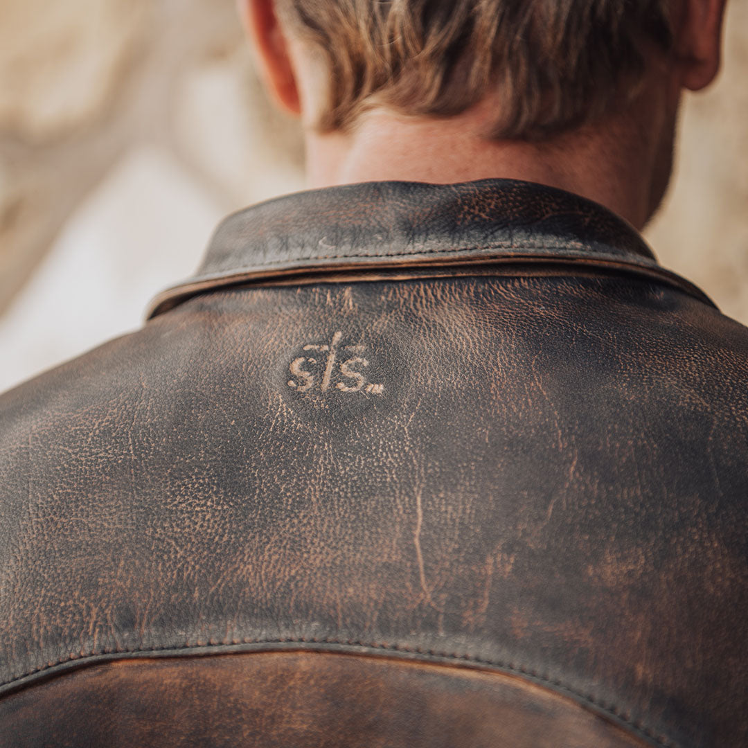 Brown genuine leather jacket with STS stamped into back.