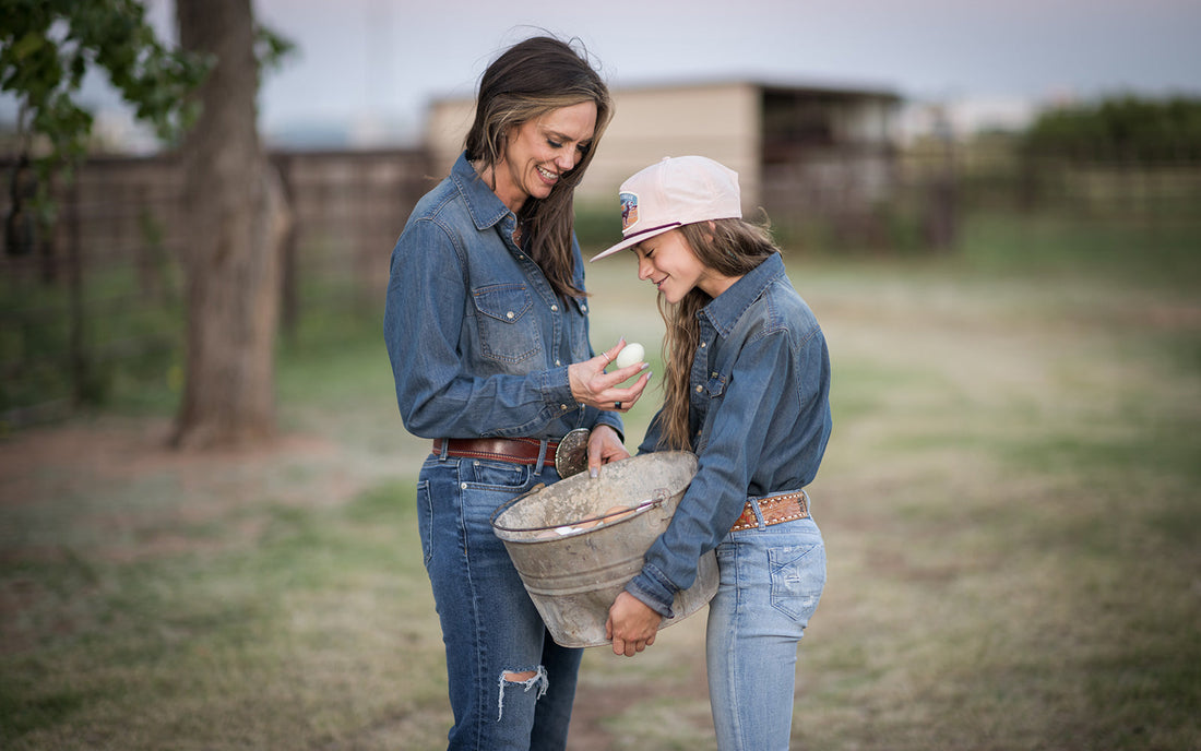 Jen Smith standing in a field with Selah Smith holding a bucket of free chicken eggs.