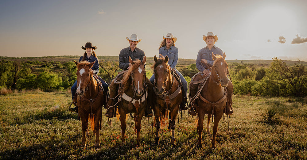 Stran and Jen Smith with their family sitting on top of horses in a pasture in Tell, Texas.