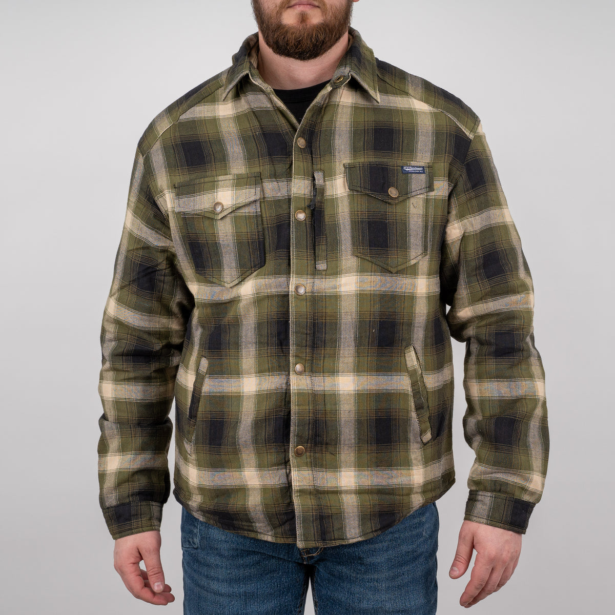 Man wearing a long-sleeved green plaid men's shirt jacket with hand warming pockets and snap closures on a gray background.