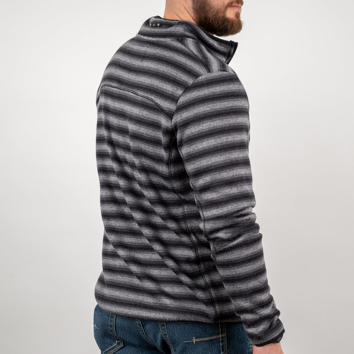 Man facing away in front of a gray background wearing a men's quarter zip pullover in black and gray stripes.