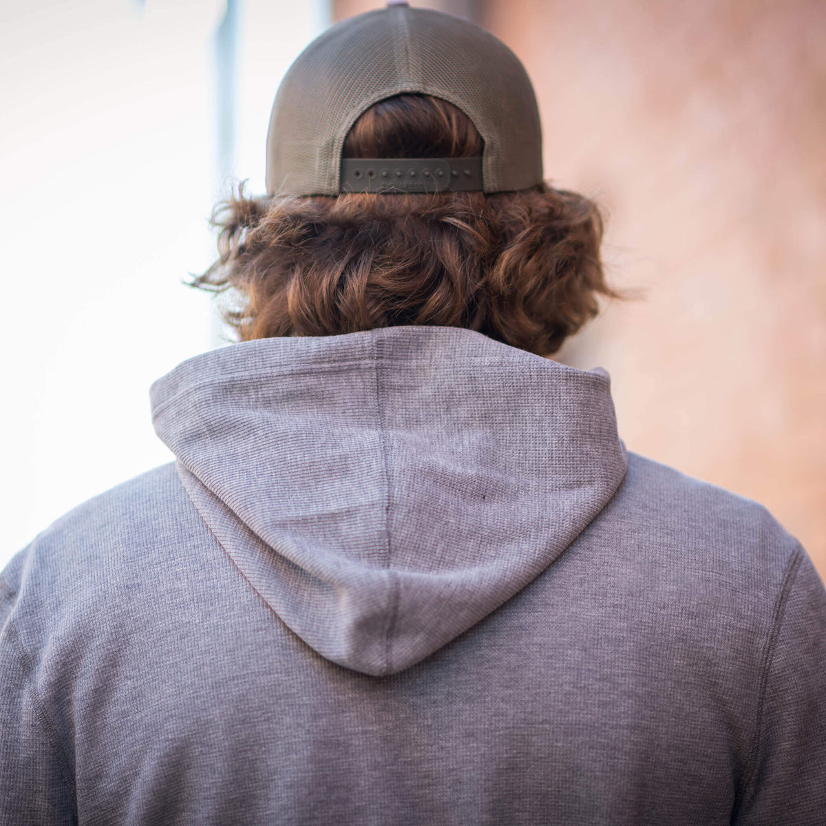 Person facing away wearing a brown hat and gray hoodie.