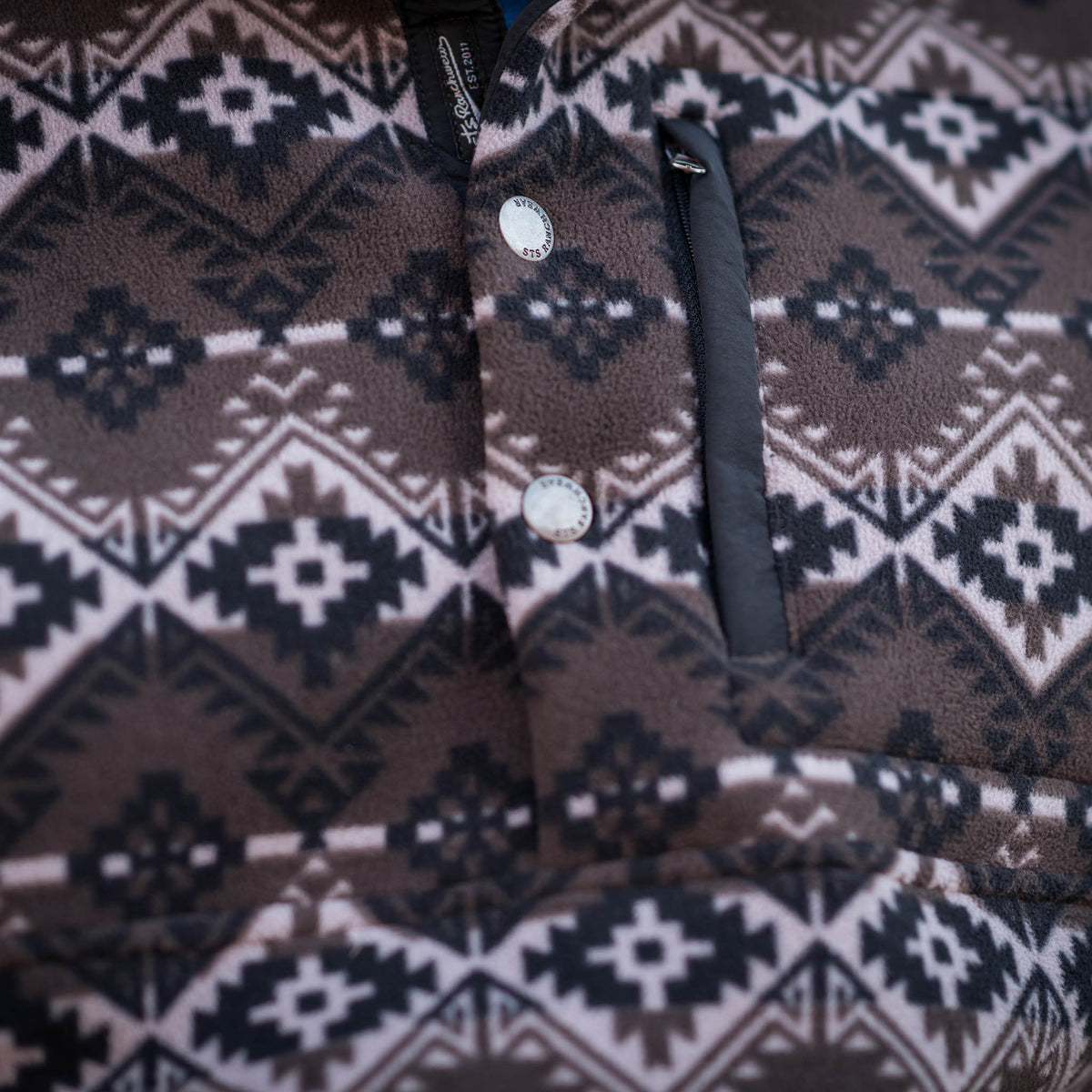 Detail of fleece on pullover sweater with a geometric pattern in black, brown, and white colors.