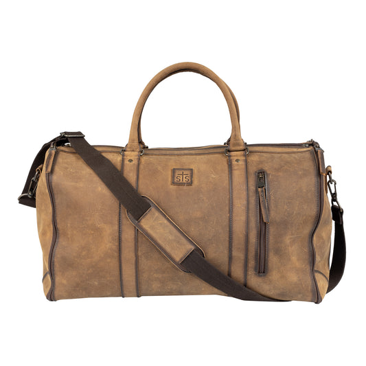 A distressed brown leather duffel bag with dark brown trim, featuring dual top handles, a detachable shoulder strap, and a small square logo patch on the front.