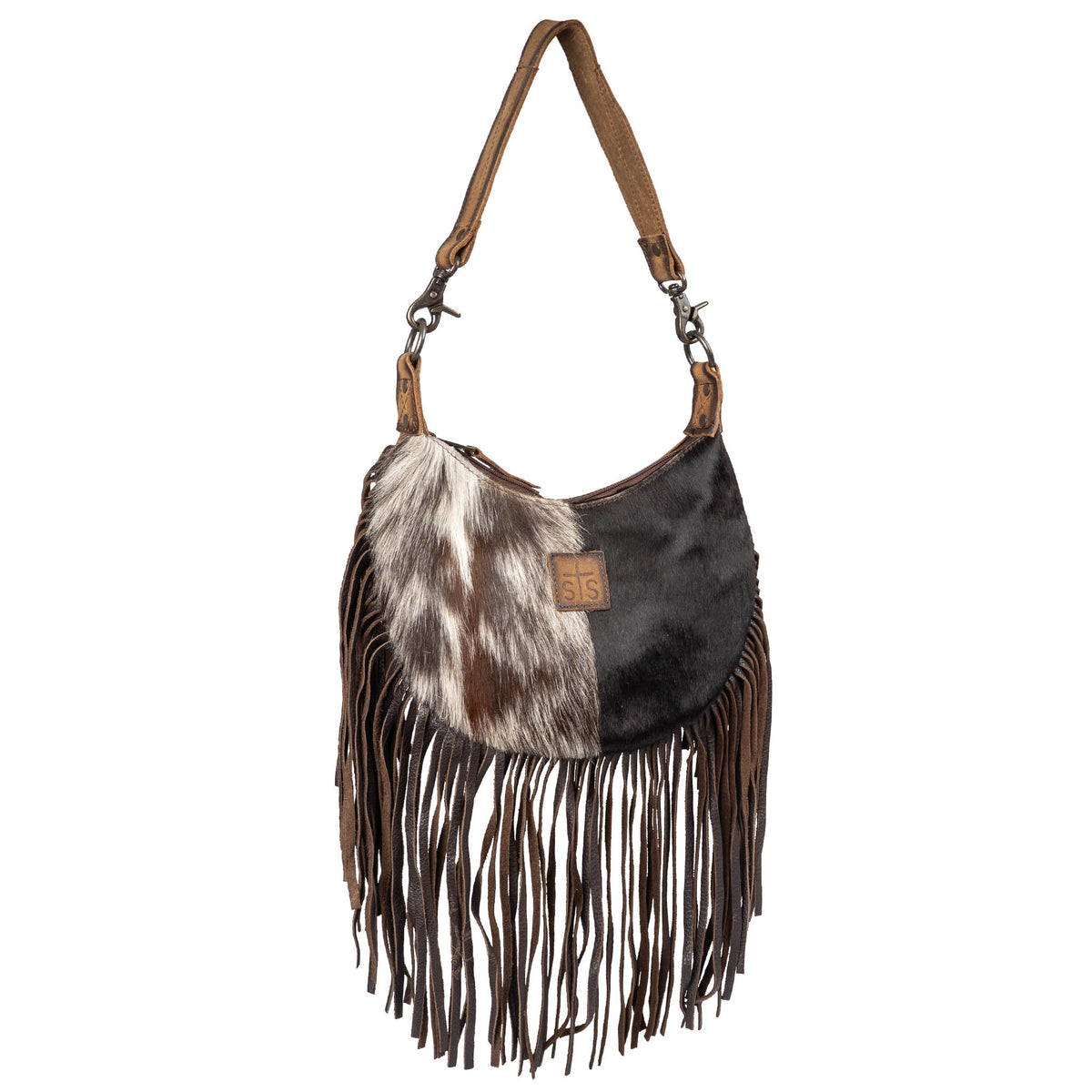 A genuine leather and hair on hide cowhide shoulder bag with leather fringe and cowhide accents and a leather patch with STS logo on a white background