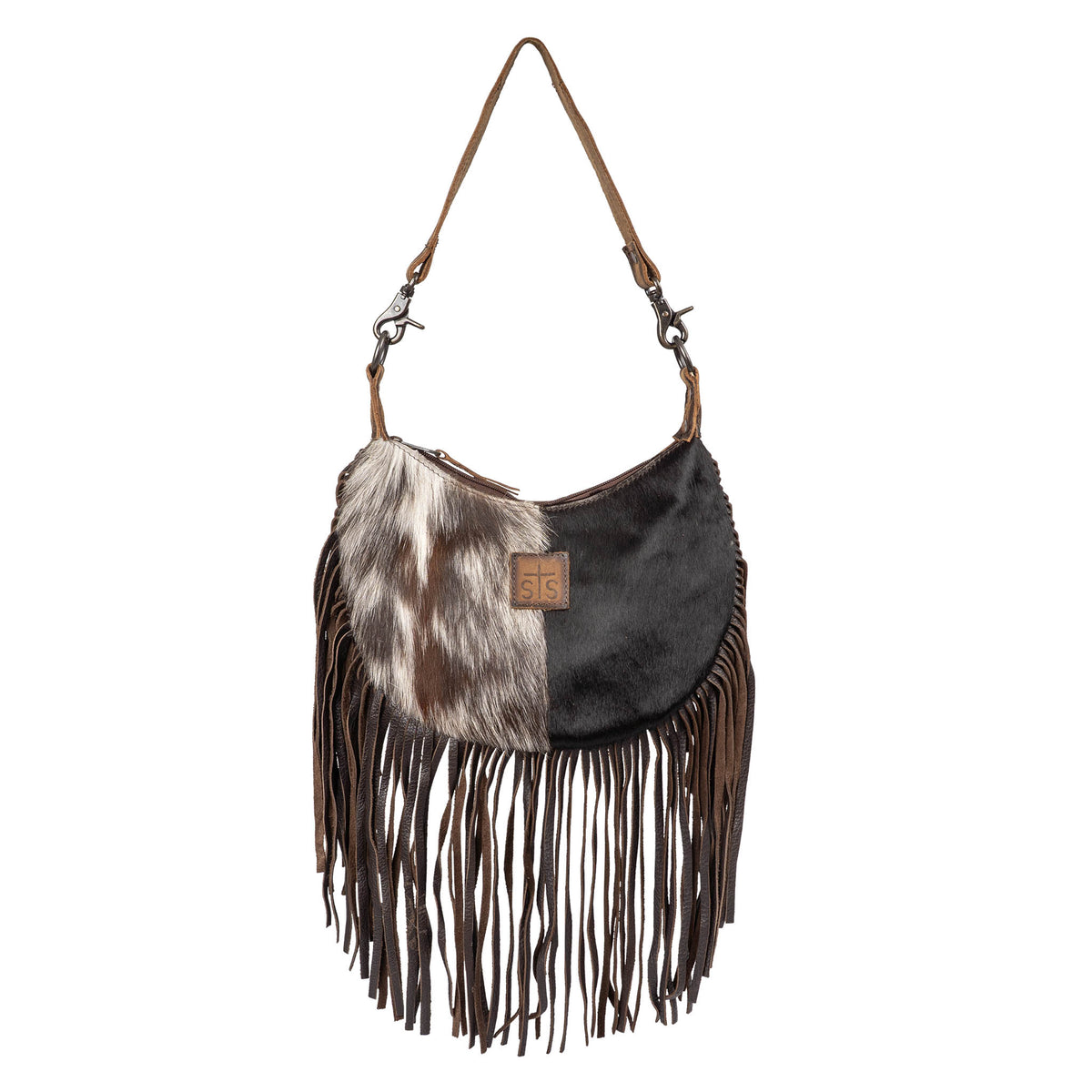A genuine leather and hair on hide cowhide shoulder bag with leather fringe and cowhide accents and a leather patch with STS logo on a white background