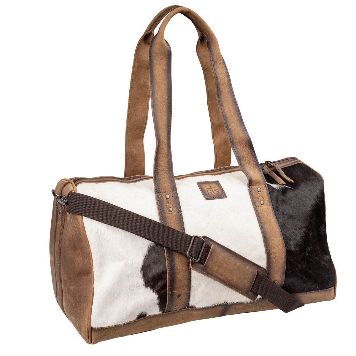 Duffle bag with brown genuine leather accents, hair on hide cowhide, leather carry handles, brown leather patch with STS logo, brown canvas shoulder strap and zip closure on a white background.