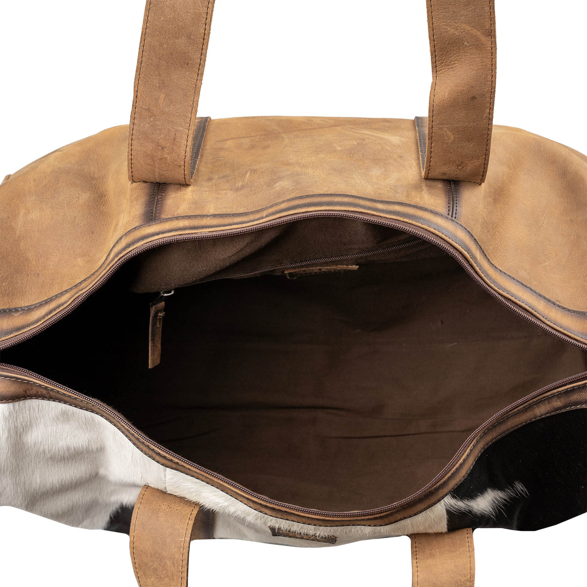 Inside compartment of duffle bag with brown genuine leather accents, hair on hide cowhide and zip closure on a white background.