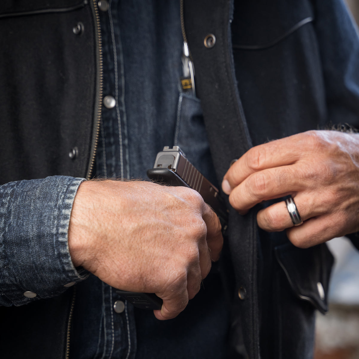 close up of a weapon being put in the conceal carry pocket in our black wool vest with leather collar front zip and snap closure and two waist pockets