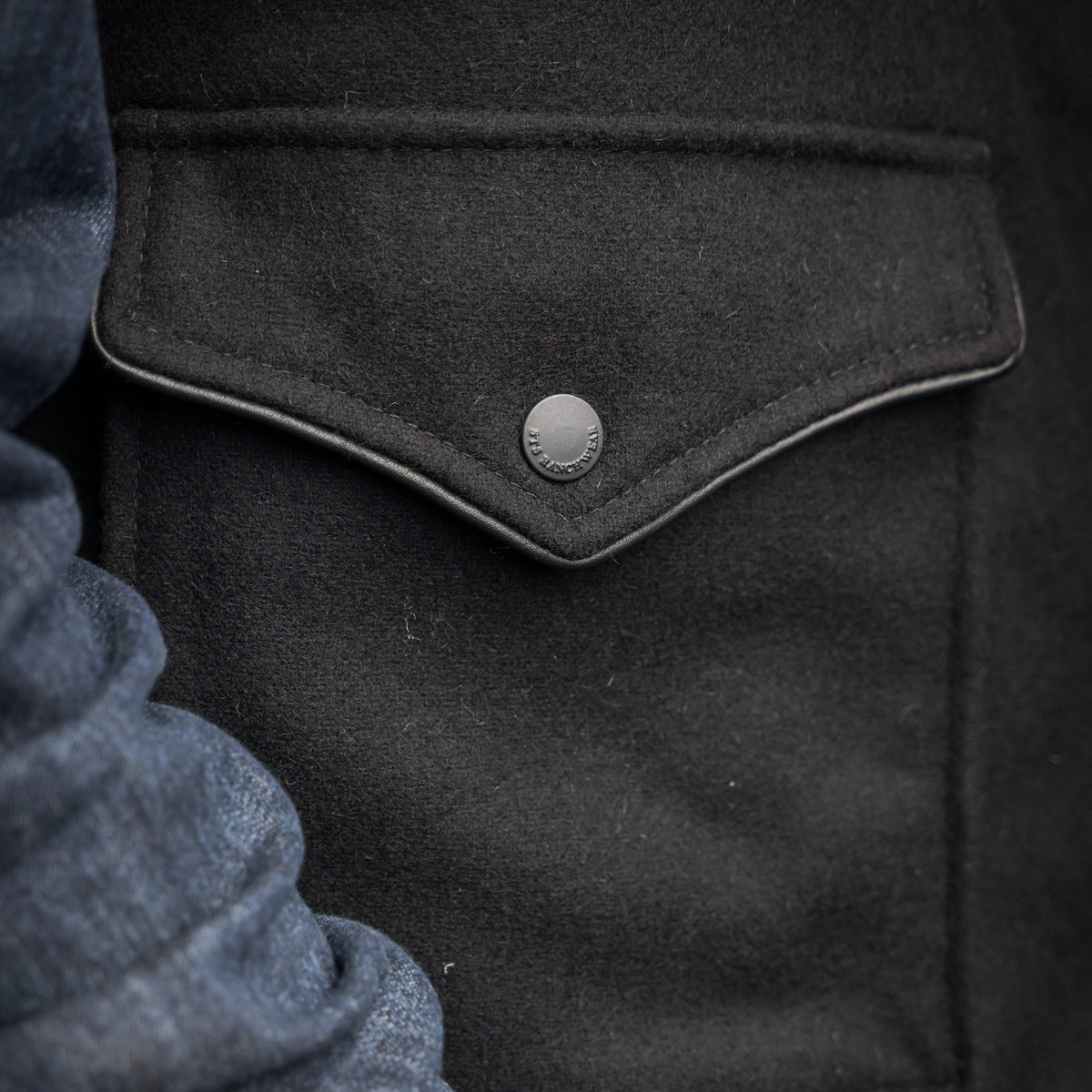 close up of the front pocket of our black wool vest with leather collar front zip and snap closure and two waist pockets 