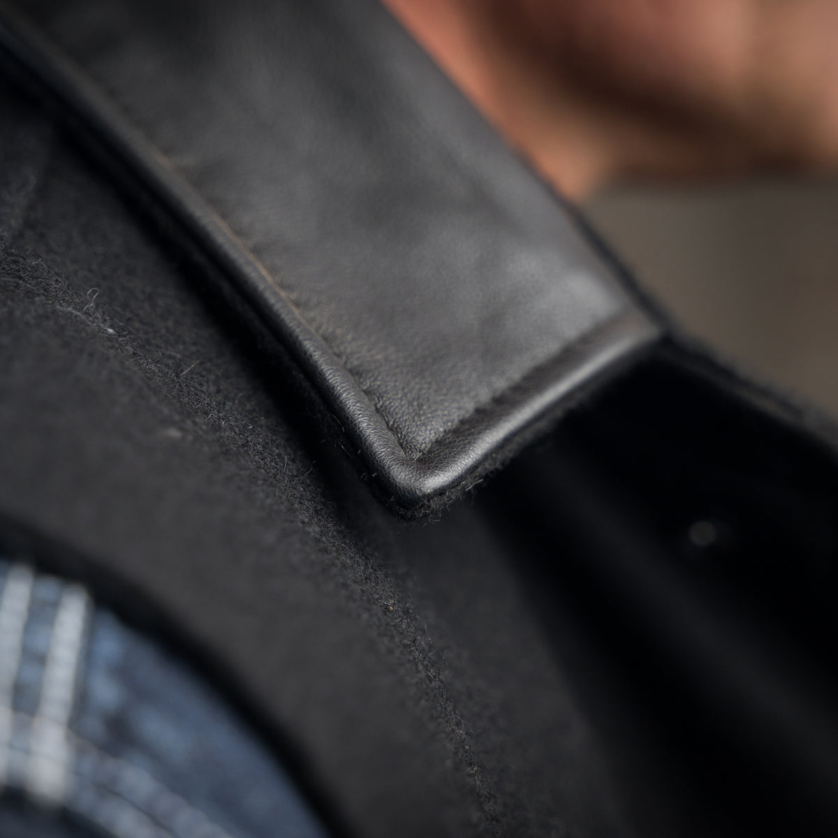 closeup of the collar on our black wool vest with leather collar front zip and snap closure and two waist pockets 
