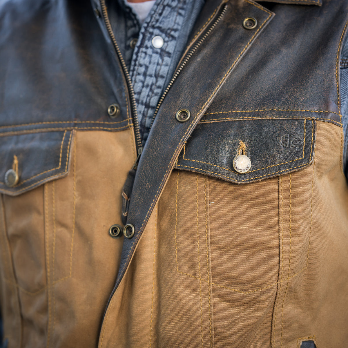 closeup of the chest of our snap and zip closure cotton canvas vest with full grain leather accents