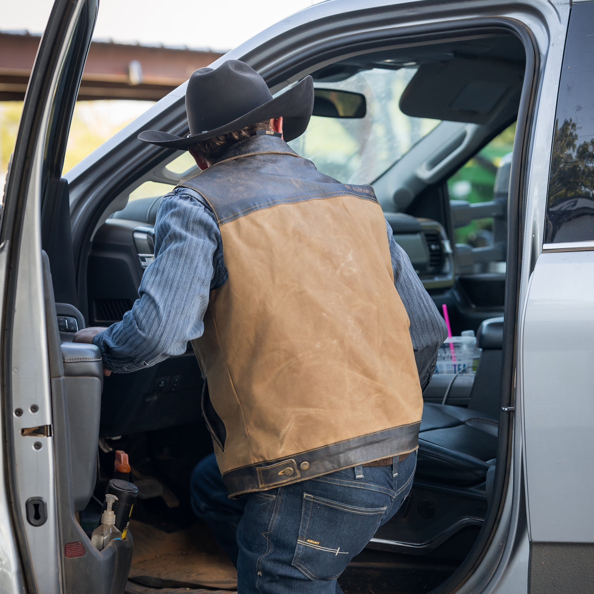 Sawyer Vest entering a truck with our snap and zip closure cotton canvas vest with full grain leather accents 