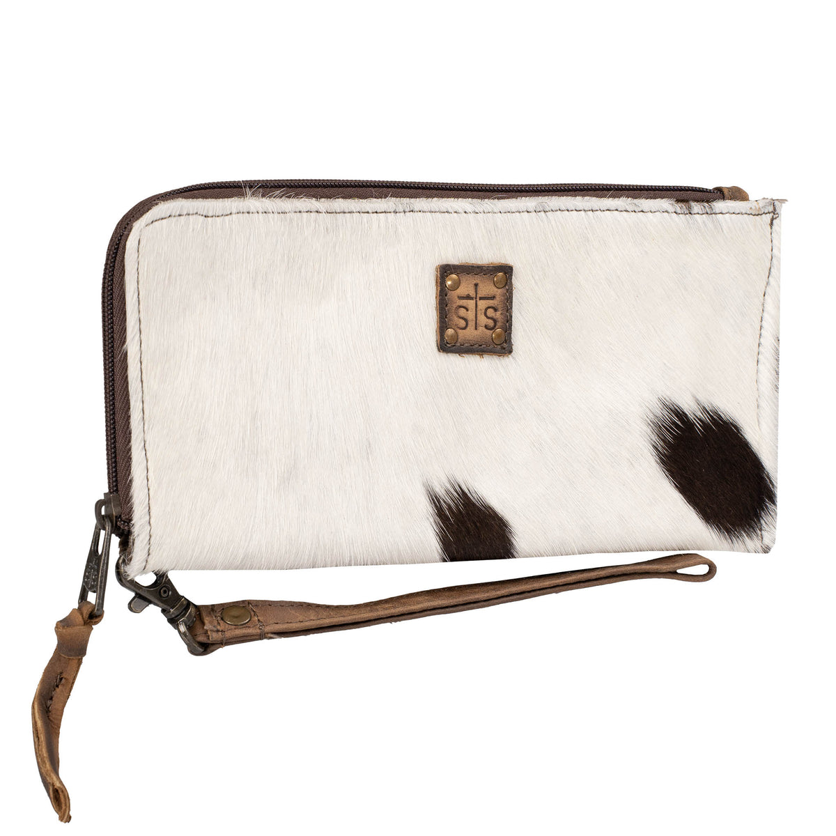 White hair on hide cowhide wallet with black spots and brown accents, zip around closure, leather STS branded patch and leather wristlet strap on a white background.