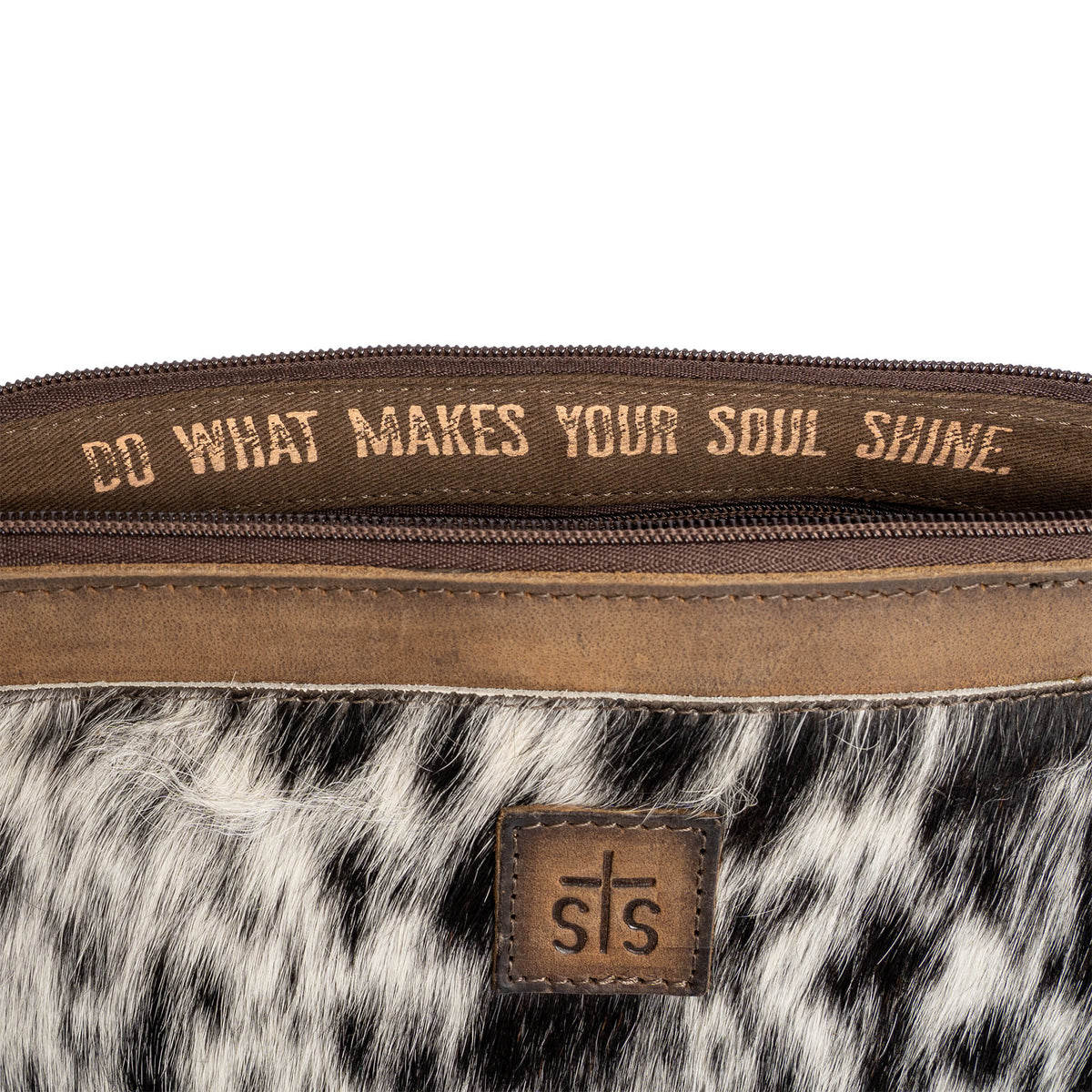 "Do what makes your soul shine." printed in gold letters in the lining of a leather shoulder bag on a white background.