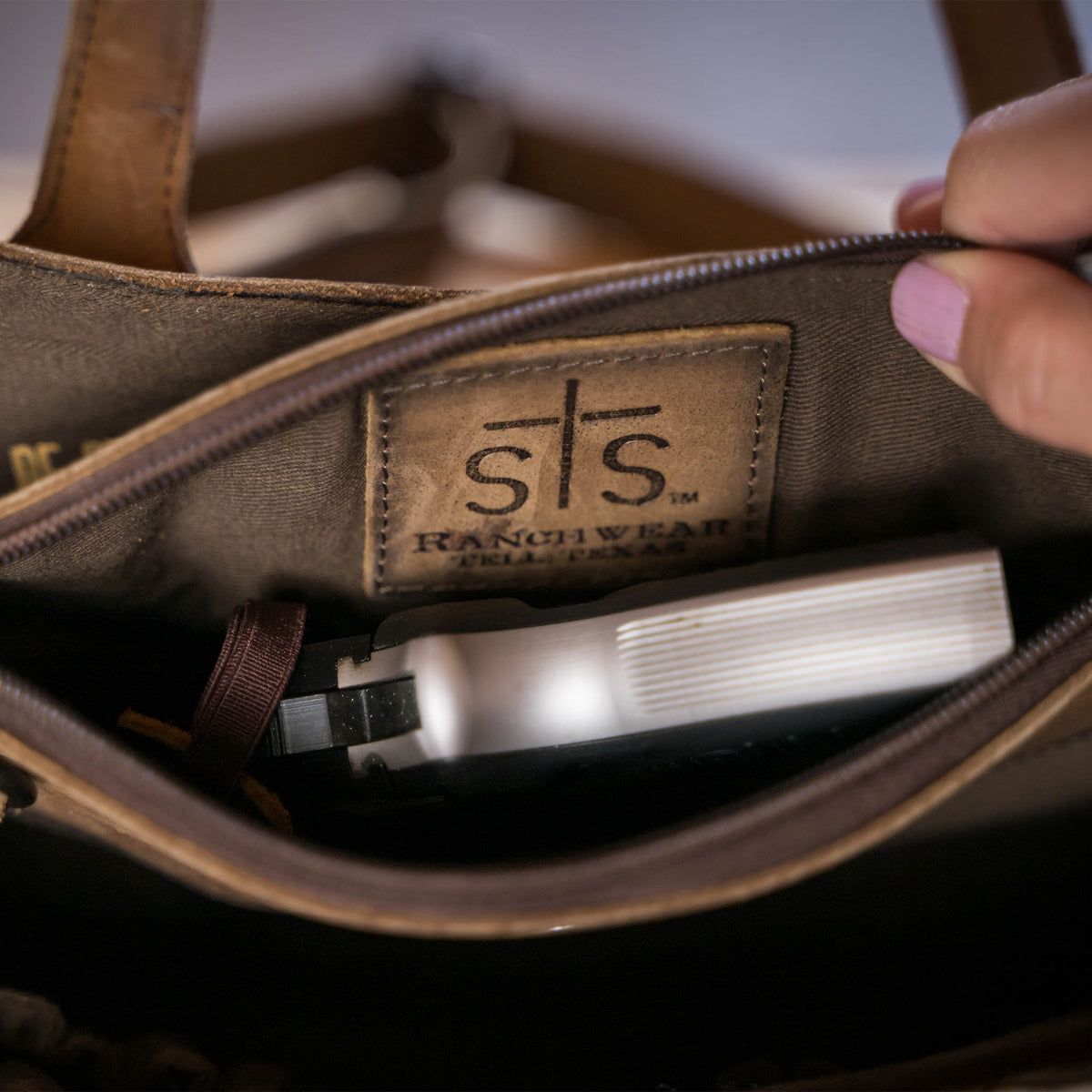 A weapon inside of the interior conceal carry compartment of a leather purse
