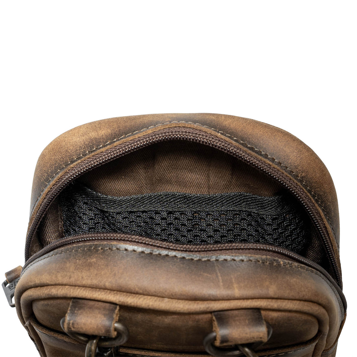 Closeup overhead view of the inside mesh pocket in a leather crossbody on a white background.
