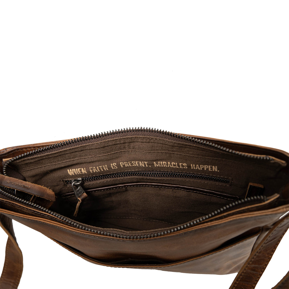 Inside of leather crossbody with zip closure pocket and inspirational quote "When faith is present, miracles happen.".