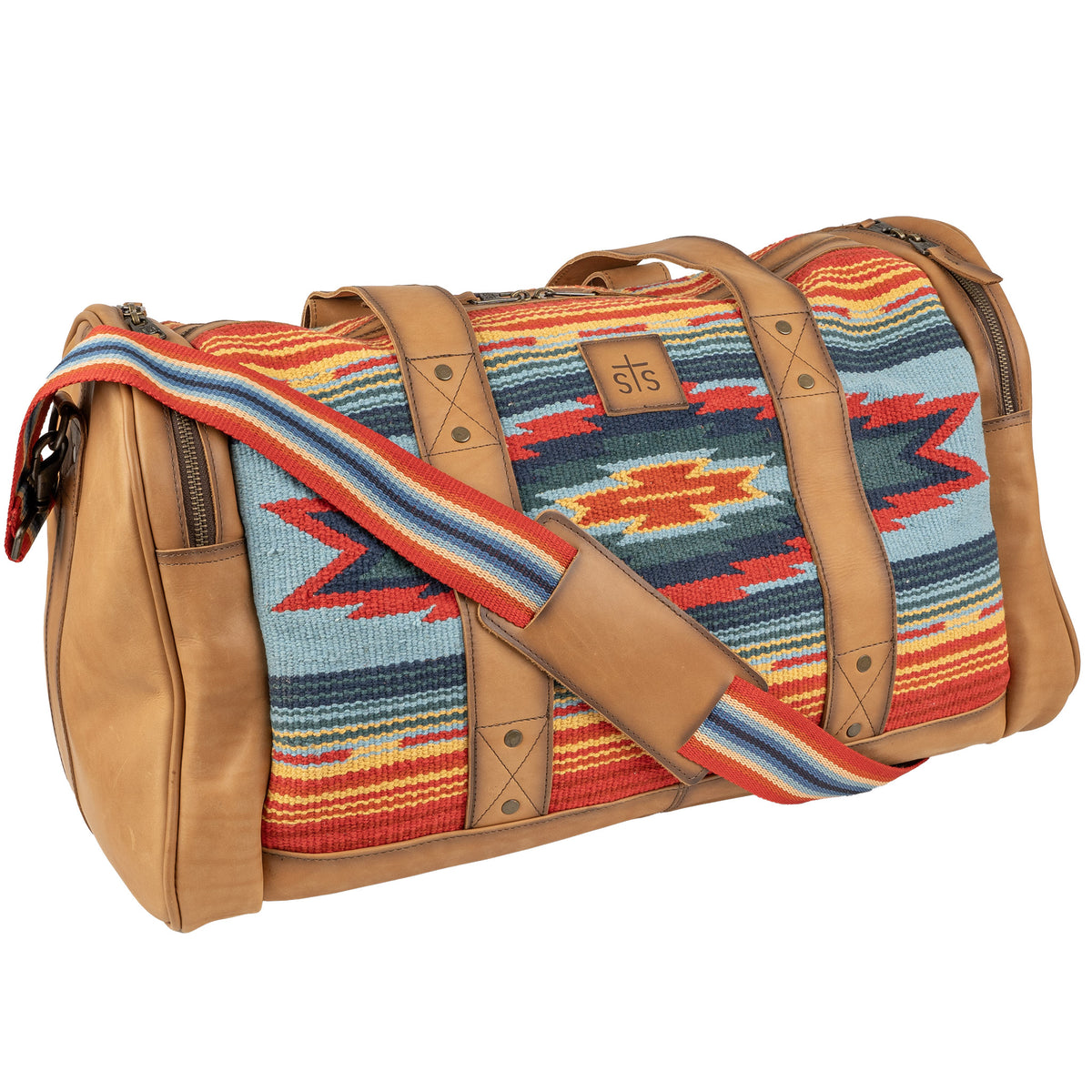 A duffle bag with a vibrant geometric pattern in red, blue, and tan colors, featuring handwoven 100% cotton shell with genuine leather accents, and a shoulder strap.
