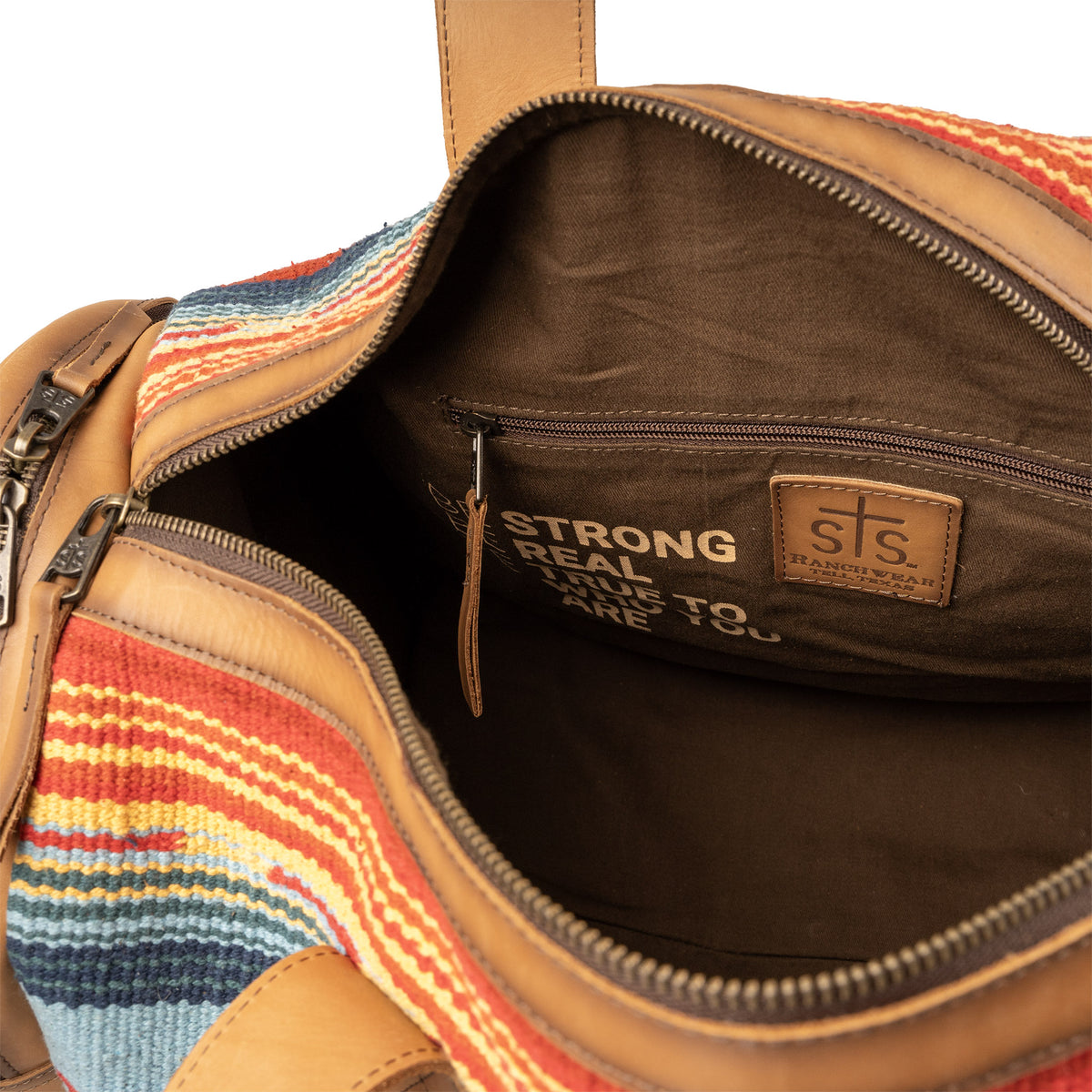 Interior of a duffle bag with brown lining, zip closure pocket and zip top closure.